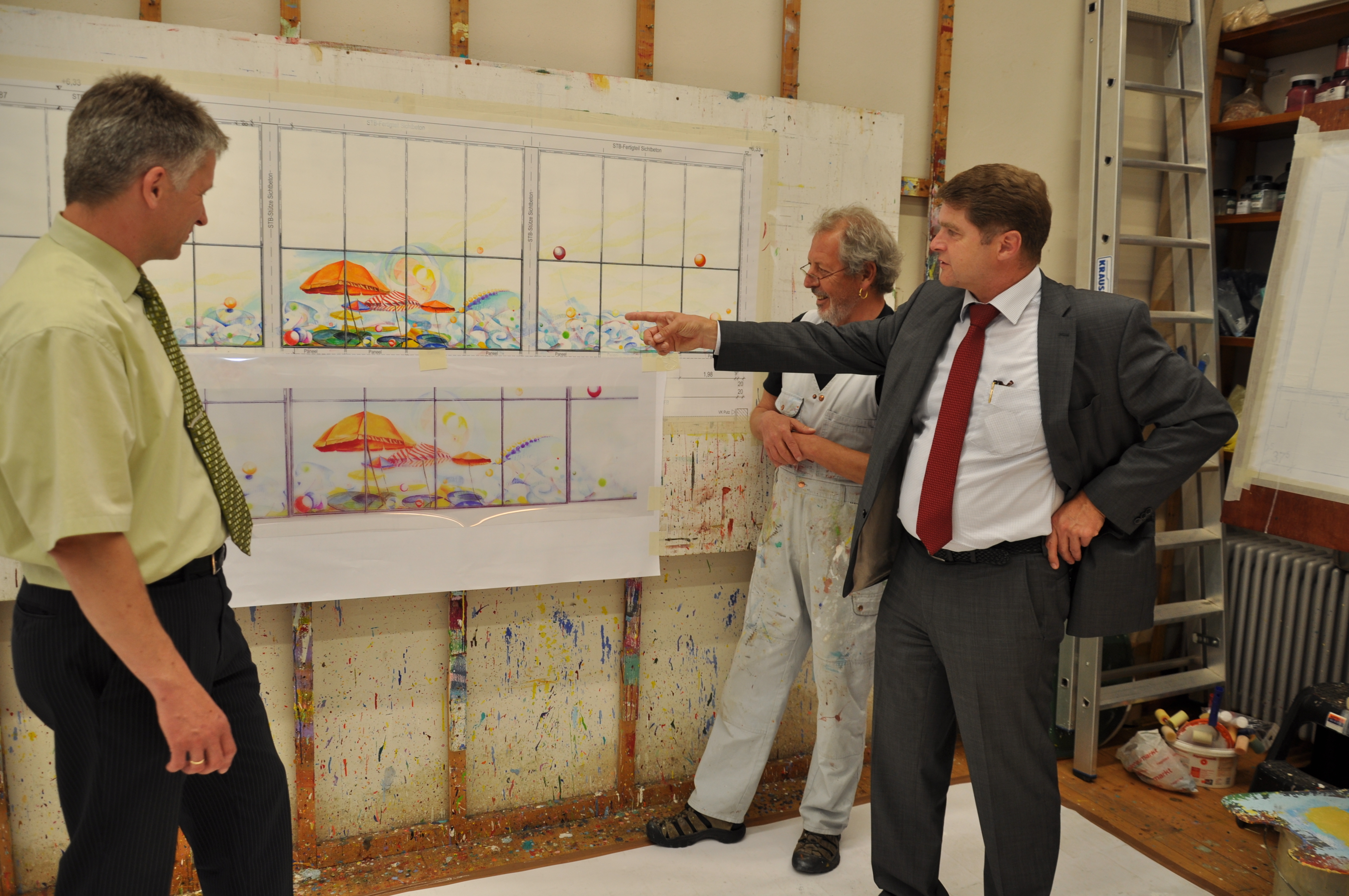 Urlaubsstimmung im Hallenbad: (von rechts) OB Martin Wolff diskutiert mit dem Künstler Willi Gilli und Stadtwerkechef Stefan Kleck über die Entwürfe für die künftige Glaskunst.