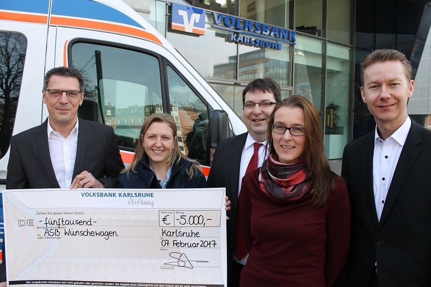 Engagement, das begeistert: Andreas Lorenz (l.) und Stefan Spohrer (r.), Vorstände der Volksbank Karlsru-he-Stiftung, freuen sich mit Tina Volz vom ASB-Wün-schewagen-Team. Mit im Bild: Joachim Schmid, Ge-schäftsführer des ASB Region Karlsruhe und die eh-renamtlich tätige Bankkauffrau Alexandra Schmidt.