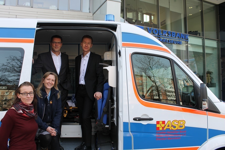 Besuch der Volksbank: Tina Volz vom ASB parkte vor der Zentrale, um den Vorständen der Volksbank Karls-ruhe-Stiftung Andreas Lorenz (l.) und Stefan Spohrer (r.) den bunten Krankentransportwagen von innen zu zeigen. Bankkauffrau Alexandra Schmidt (mit Brille) machte auf das Projekt Wünschewagen aufmerksam.