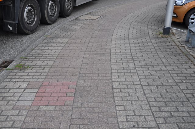 Verblichener Radwegebelag an der Zähringer Straße: Das ursprüngliche Rot der Pflastersteine ist nur noch an der ausgebesserten Stelle erkennbar.