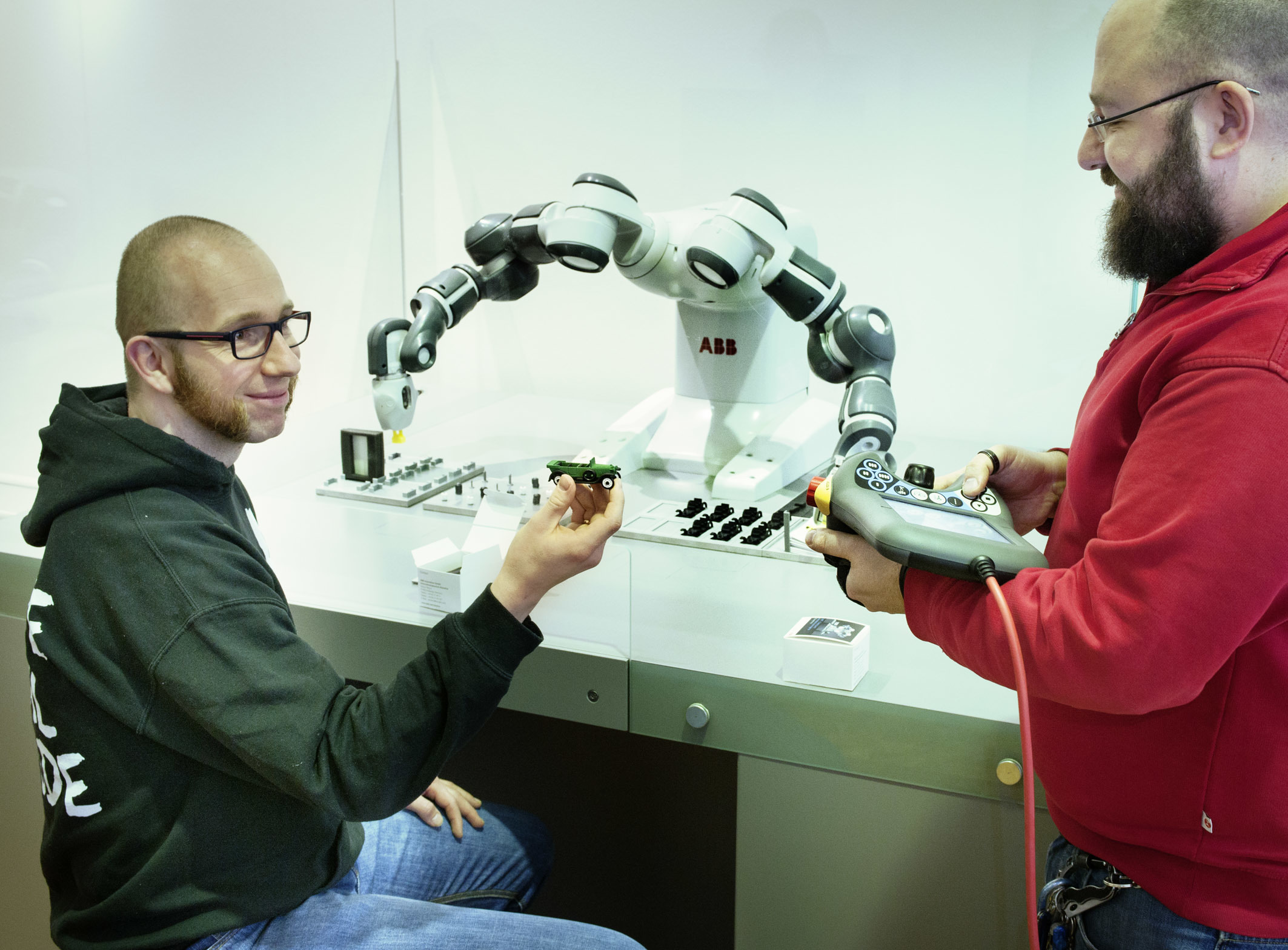 Ein Roboter baut gemeinsam mit Besuchern ein Modellauto zusammen und verdeutlicht auf diese Weise, wie die vollautomatisierte Fertigung in der heutigen Industrie funktioniert.