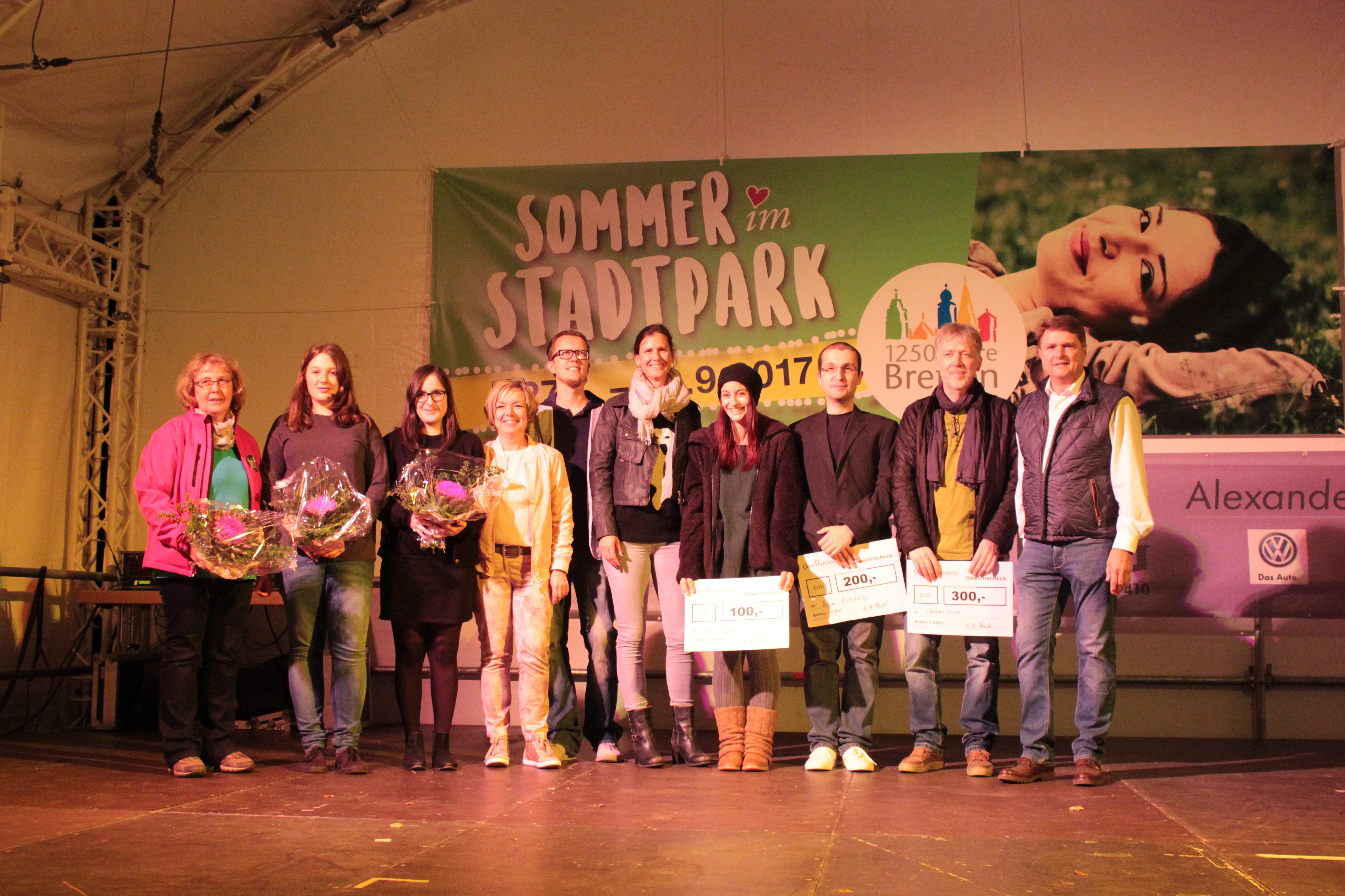 Die Gewinner des Poetry Slam-Contests im Stadtpark (mit Schecks) mit den Moderatoren und Veranstaltern.