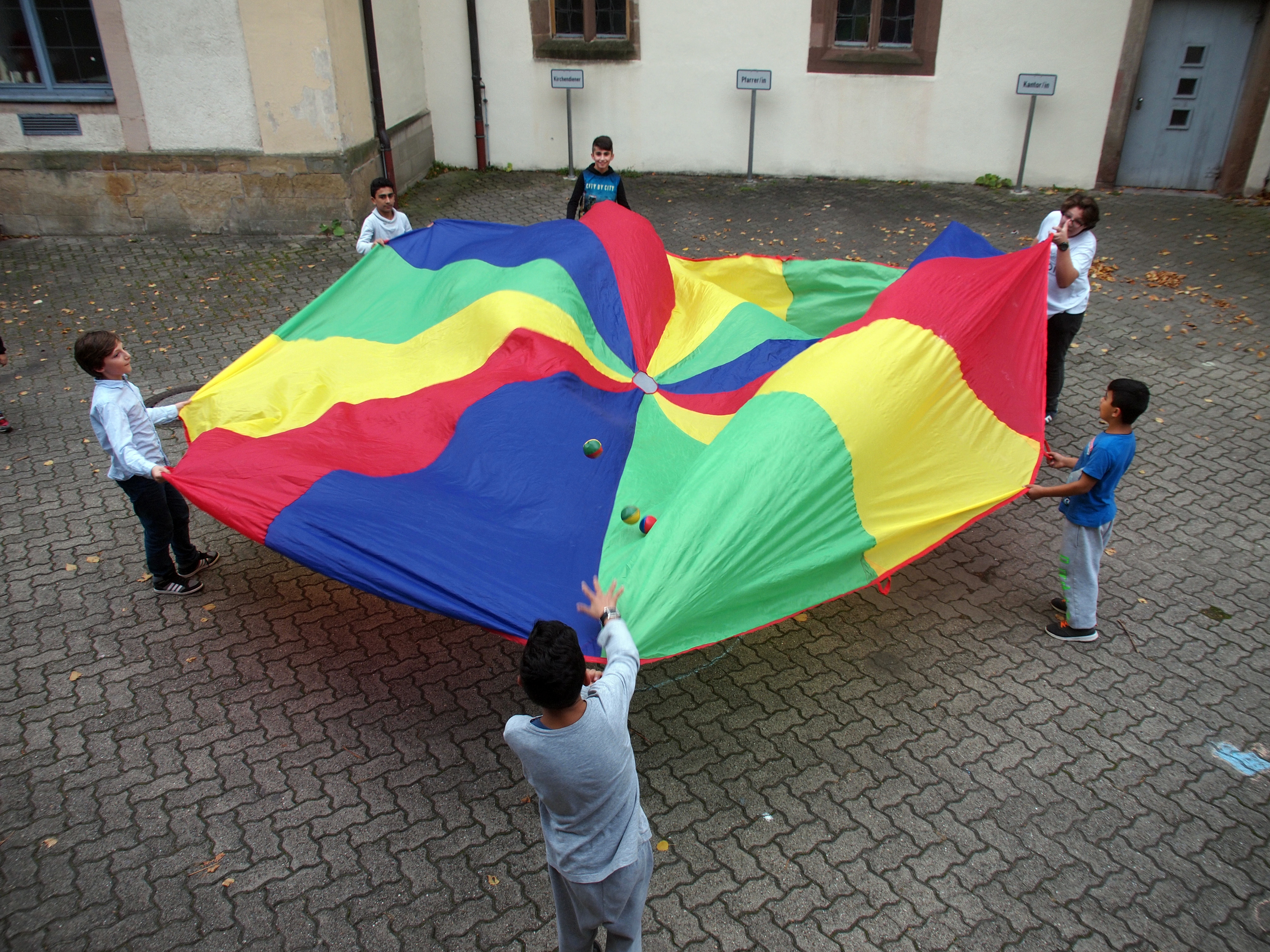 Kinder des Café International spielen mit dem gespendeten Schwungtuch