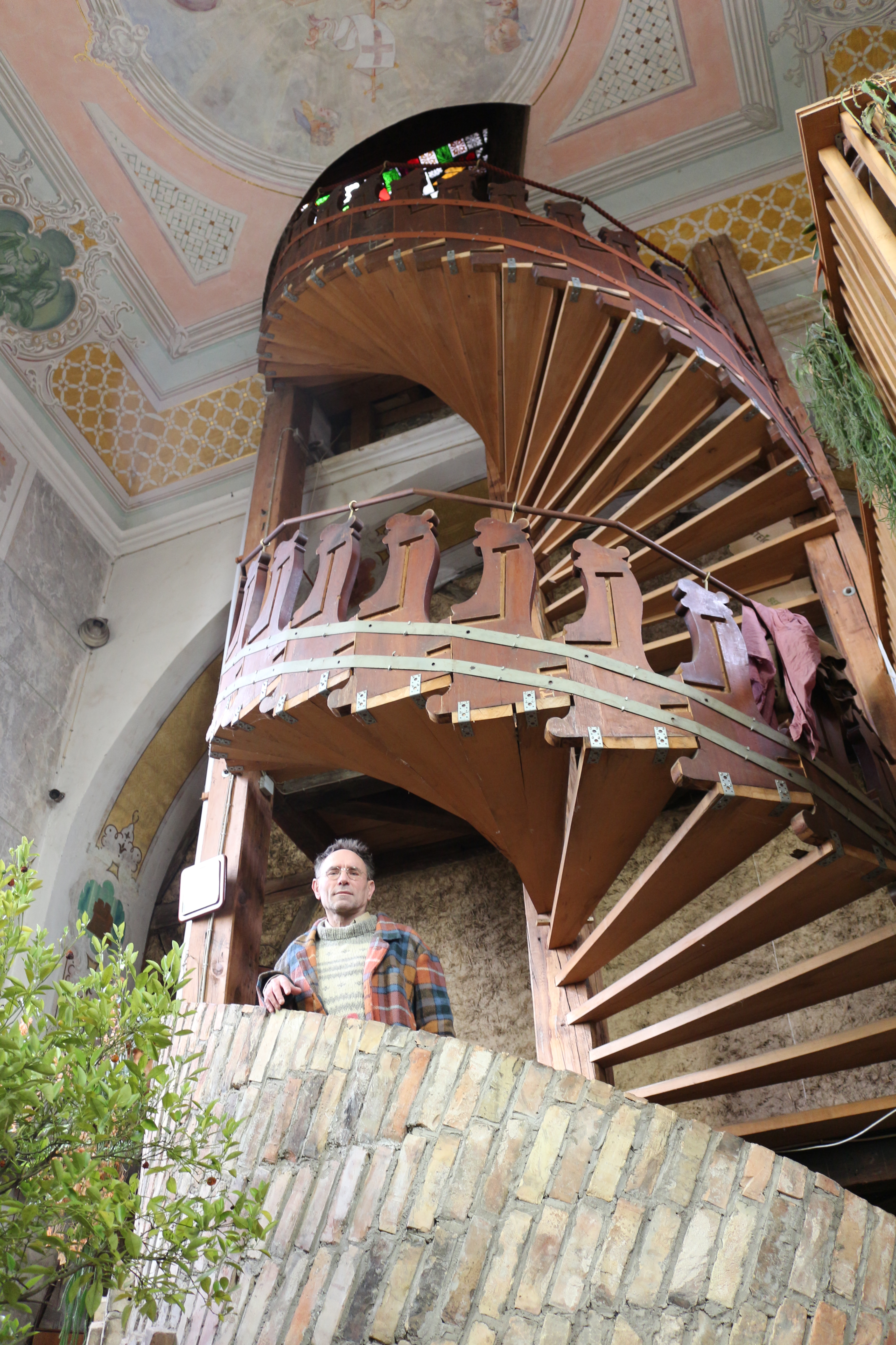 Die Wendeltreppe säumt ein Geländer aus den Seitenteilen der alten Kirchenbänke.