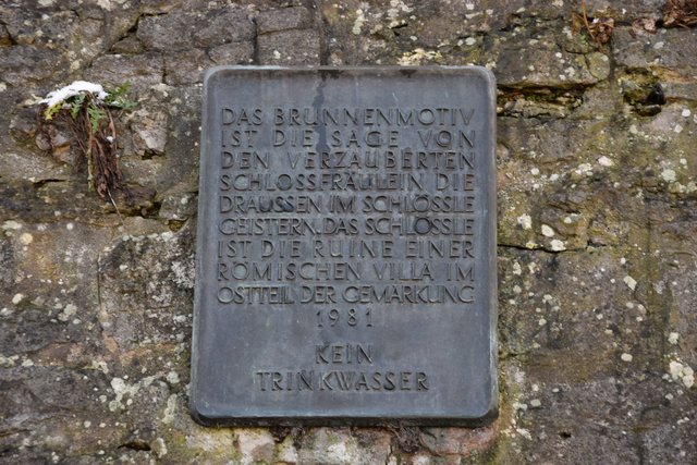 Eine Tafel an der Kirchmauer erklärt die Hintergründe des Brunnenmotivs. Foto: ch