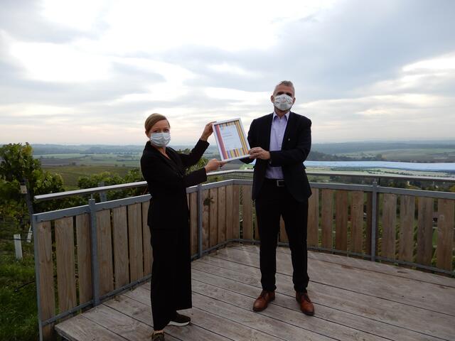 Übergabe der Urkunde „Weinsüden Weinort“ durch Christina Lennhof, Geschäftsführerin KST, an Sachsenheims Bürgermeister Holger Albrich vor der Kulisse der Sachsenheimer Weinlandschaft | Foto: Kraichgau-Stromberg Tourismus e.V.