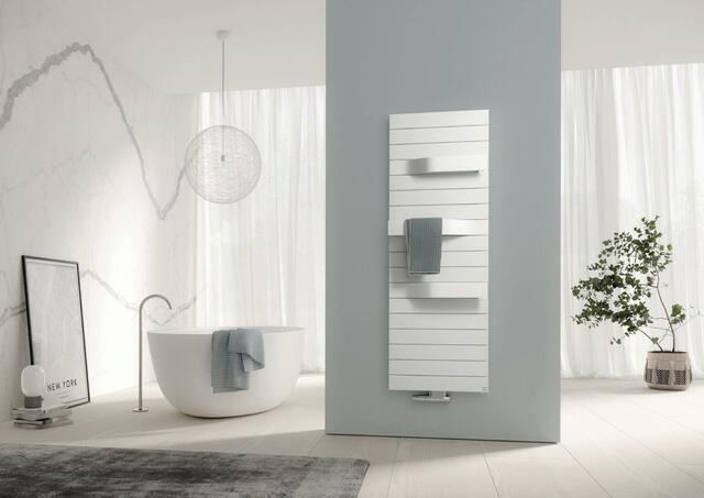 Mit seiner klaren, harmonischen Form und den charakteristischen Fugen fügt sich Tabeo perfekt in jedes Raumbild. In die dynamisch aus der Fläche heraustretenden Bügel lassen sich Handtücher zum Vorwärmen bequem einhängen. Wie viele der Design- und Badheizkörper gibt es ihn auch als rein elektrische Variante oder mit Elektro-Zusatzbetrieb – für rasches Heizen bei kurzfristigem Bedarf. Foto: Kermi GmbH/akz-o