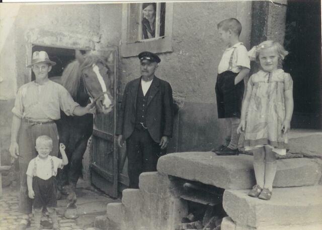 André Petit (links) in den 1940er Jahren in Neibsheim mit den Kratzmeier-Kindern aus der Nachbarschaft, einem unbekannten Herrn und seiner „Dienstherrin“ Maria Strobel am Fenster. | Foto: privat