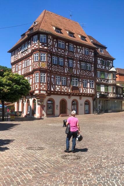 Diese Bikerin legt im baden-württembergischen Mosbach eine Pause ein und blickt auf ein besonderes Prachtstück unter den Fachwerkhäusern. Die Holzbalken an der Fassade sind durch Schnitzereien und Bemalungen verziert. | Foto: DJD/Deutsche Fachwerk Straße/Motorradstrassen/Peter Wahl