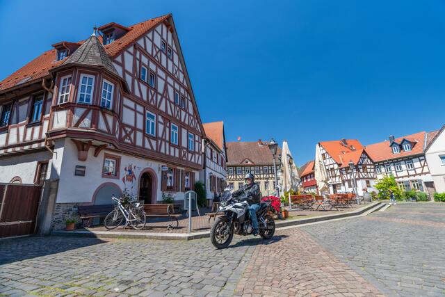 Unterwegs auf der Deutschen Fachwerkstraße: Auch mit dem Motorrad kann man auf den Spuren der Vergangenheit unterwegs sein, wie hier im hessischen Hanau-Steinheim. | Foto: DJD/Deutsche Fachwerk Straße/Motorradstrassen/Peter Wahl