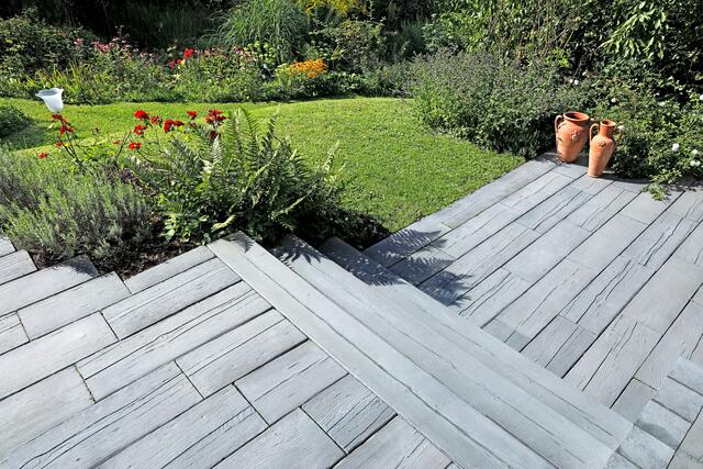 Die unterschiedlichen Maserungen mit feinen Vertiefungen und charakteristischen Astlöchern lassen die Terrassendielen wie echtes Holz wirken. | Foto: DJD/MAHORA/braun-steine