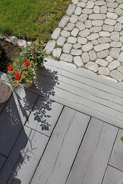 Eleganter Übergang: Die Terrassendielen in Holzoptik können im Außenbereich spannende Akzente setzen. | Foto: DJD/MAHORA/braun-steine/www.photodesign-buhl.de